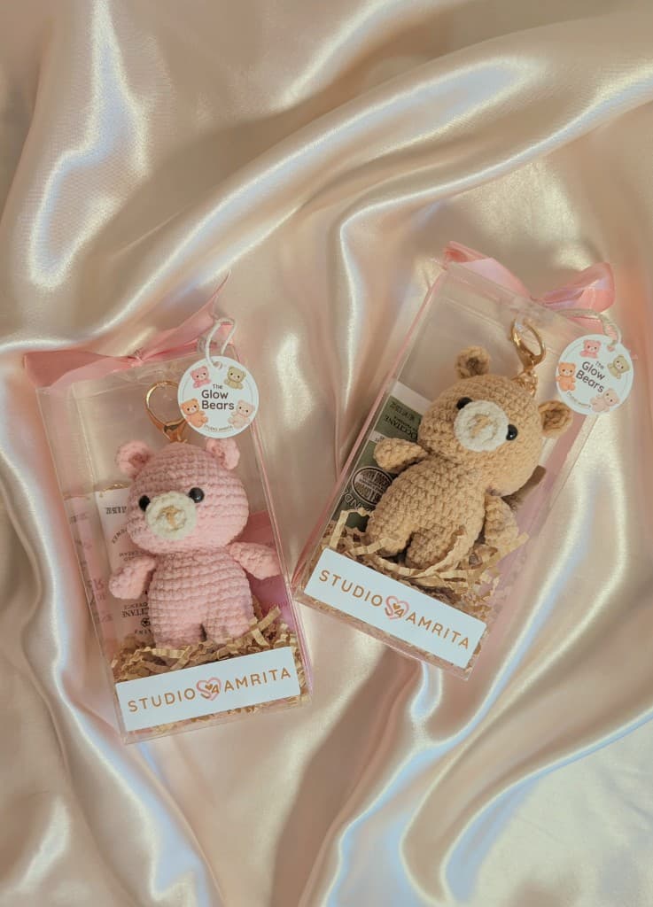 Two Essential Glow Bear gift sets in sakura pink and honey brown on satin packaging